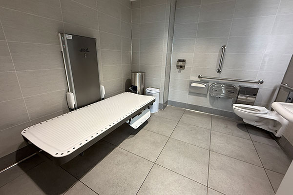 Accessible restroom with adult changing table, grab bars, and accessible toilet fixtures.